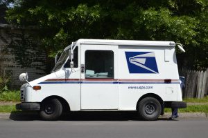 new year's: usps truck in front of green trees on the side of the road