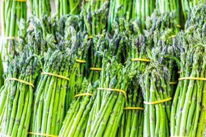 Closeup of many asparagus bunches on display at farmers market during summer