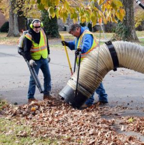 leaf collection: two men holding a large vacuum collection leaves