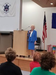 older woman in a blue suit talking on stage