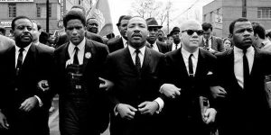 martin luther king jr. linking arms with other men in a black and white photo