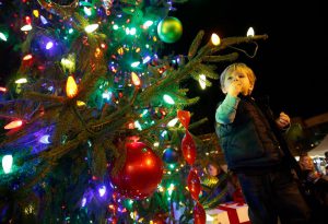 christmas tree with colorful lights and a young boy looking at it