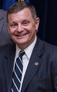 health: a man in a suit smiling at camera