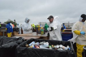 Hazardous Household Materials: people in white hazmat suits sorting materials