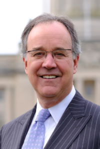 Business News Kentucky Chamber: man in a suit and glasses smiling at the camera