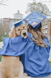 a golden retriever in a graduation cap and a woman in a cap and gown