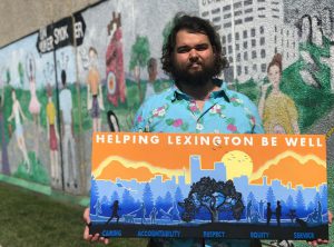 Health: a man holding a painting with a mural behind him