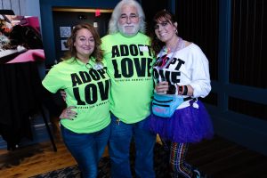 Pet: group of people wearing lime green shirt that says adopt love and a girl dressed from the 80's
