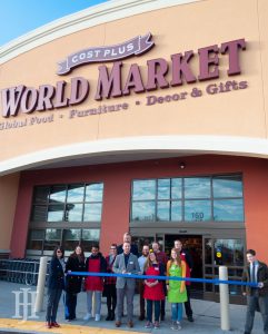 World Market: group of people standing outside of a building with ribbon